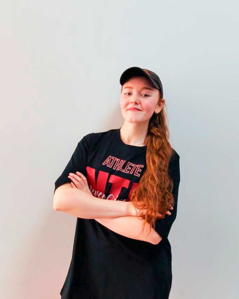 Miki con los brazos cruzados frente a una pared blanca